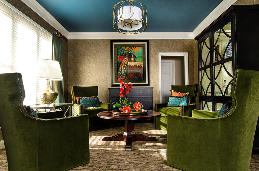 Lounge room with blue ceilings, green upholstered swivel chairs and peacock artwork