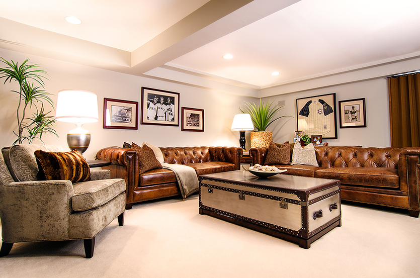 Two brown leather sofas with tan upholstered chair, trunk coffee table and vintage-style framed Chicago sports memorabilia