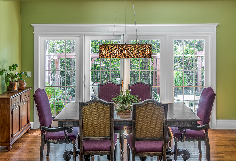 Green dining room with plum velvet chairs and rectangular twig chandelier