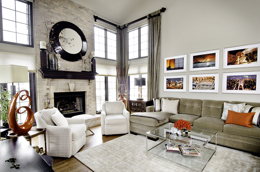 Two story family room with fireplace, light upholstery and orange accents