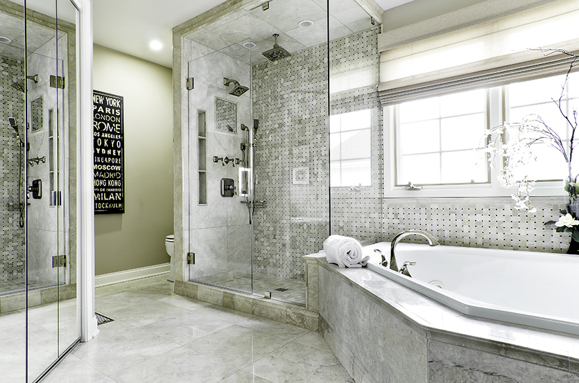 Grey marble tiled bathroom with spa tub and glass shower with rainfall showerhead