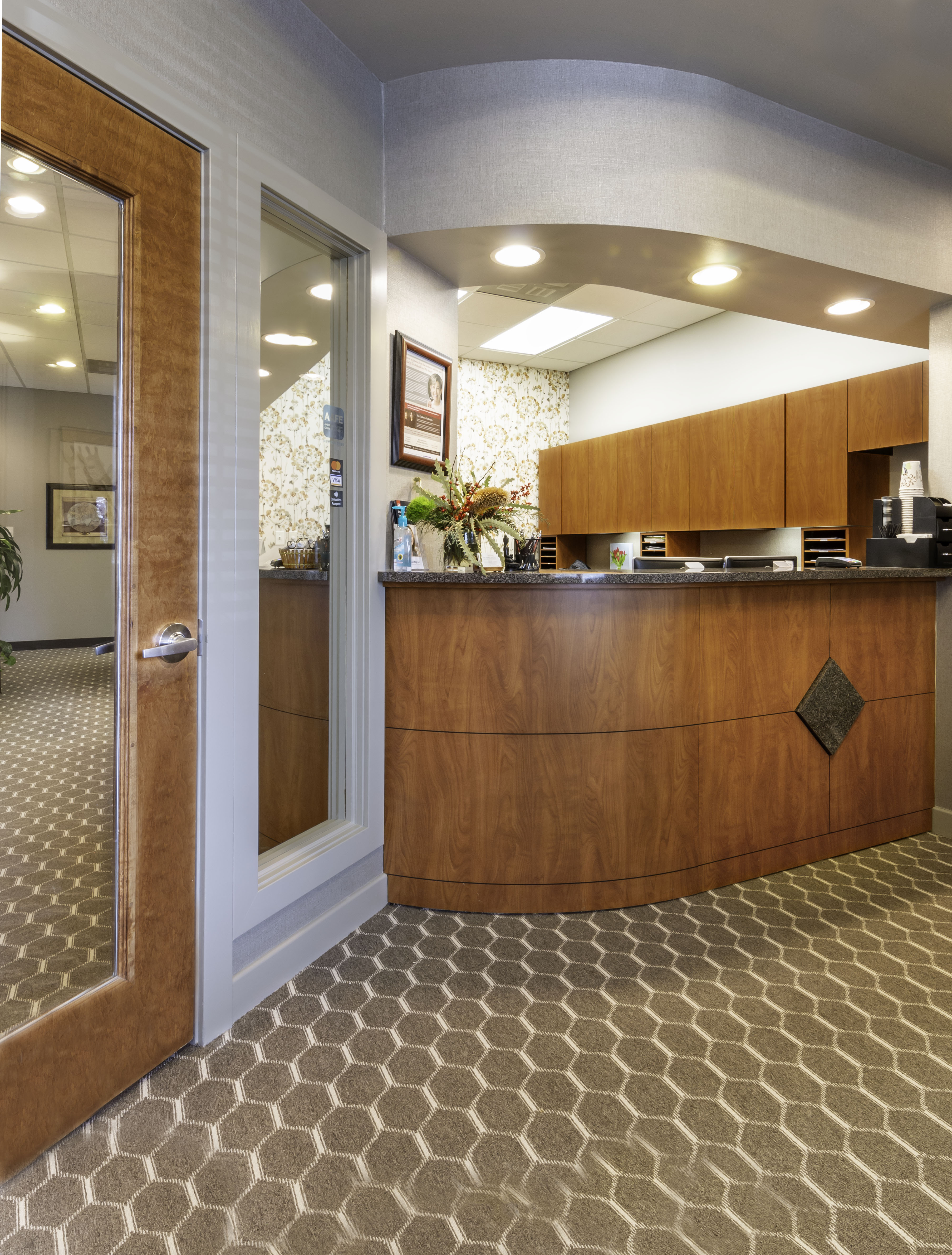 Reception area of dentist office with wood counter and tan patterned carpet