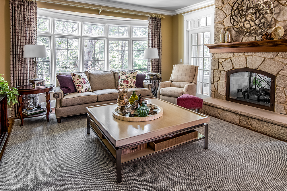Tan and plum furnishings in living room with large stone fireplace