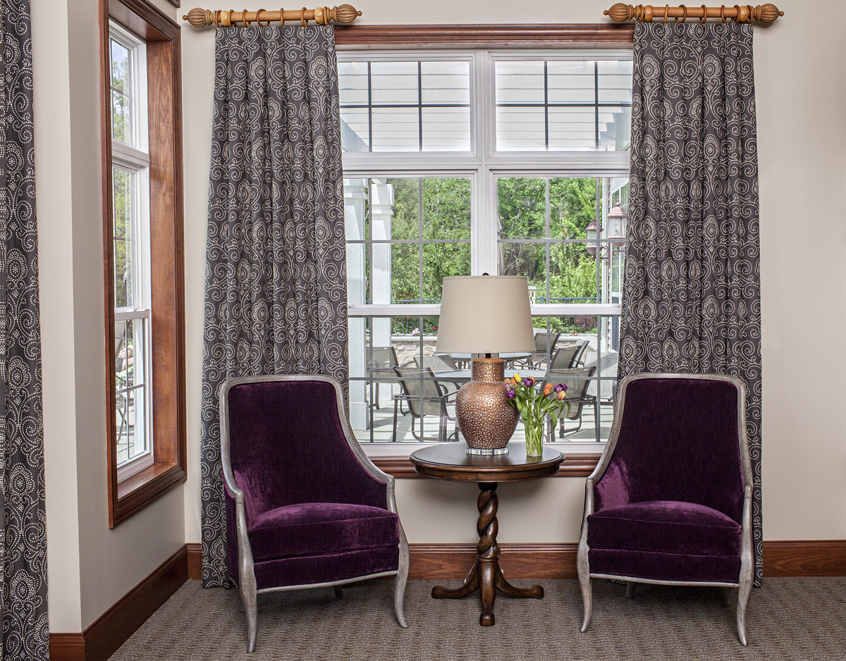 Pair of purple velvet chairs in front of window with long drapery