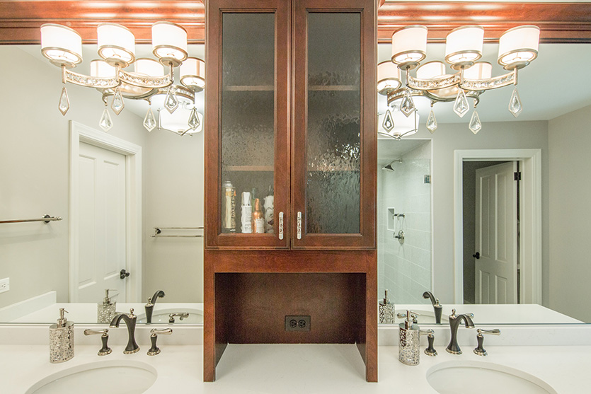 Dual sink dark wood vanity and crystal drop light fixtures on mirror