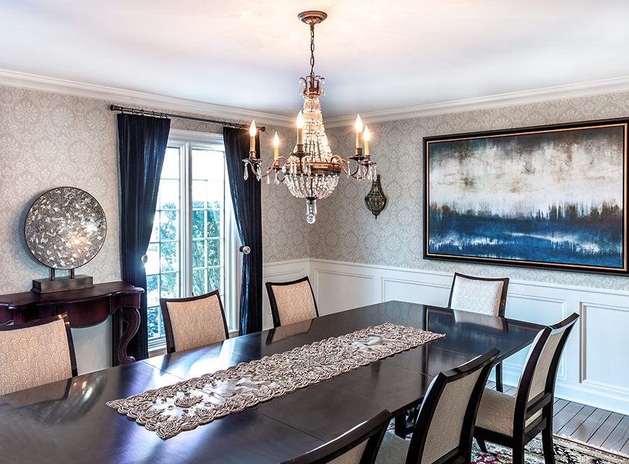 Dining room with formal chandelier, navy drapery and modern artwork