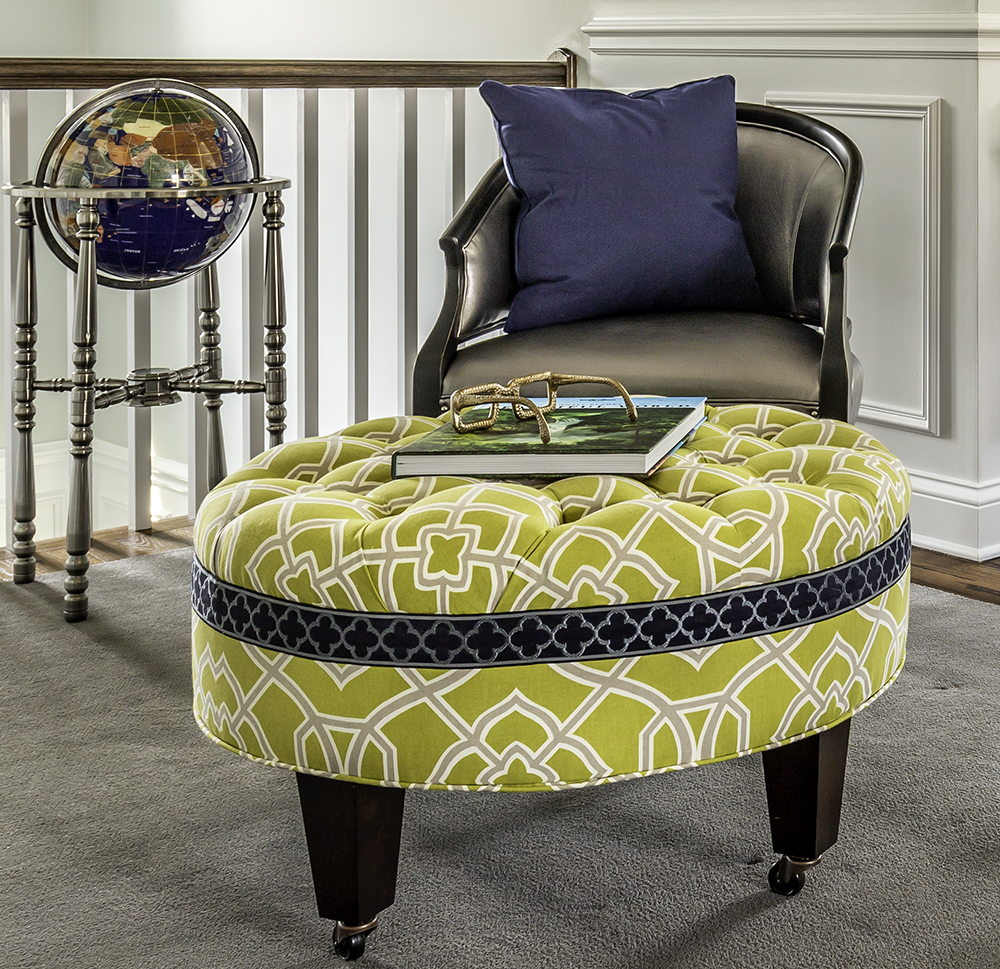 Grey chair with blue pillow, green upholstered ottoman and blue globe on silver stand