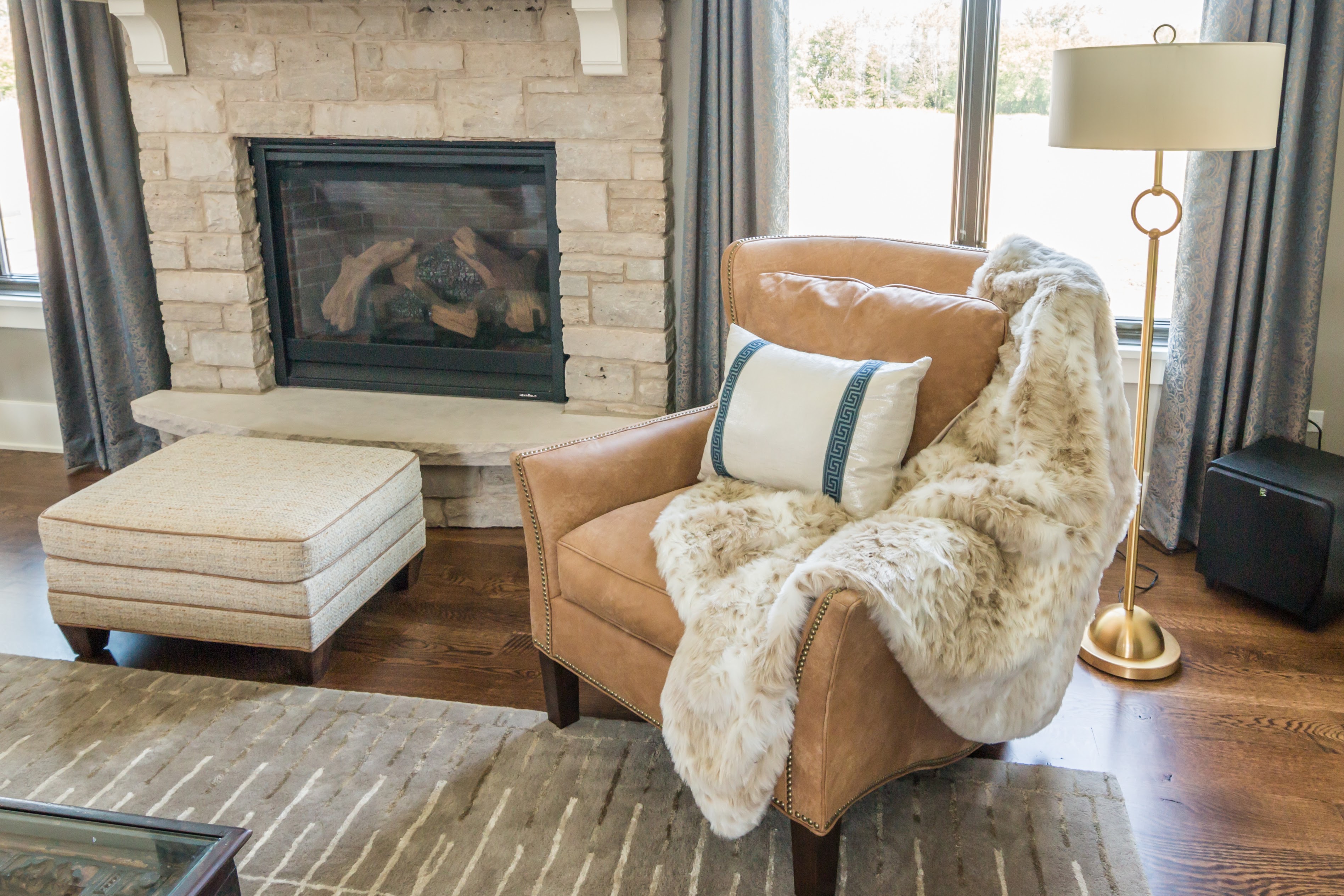 Light brown leather chair beside stone fireplace with faux fur throw blanket