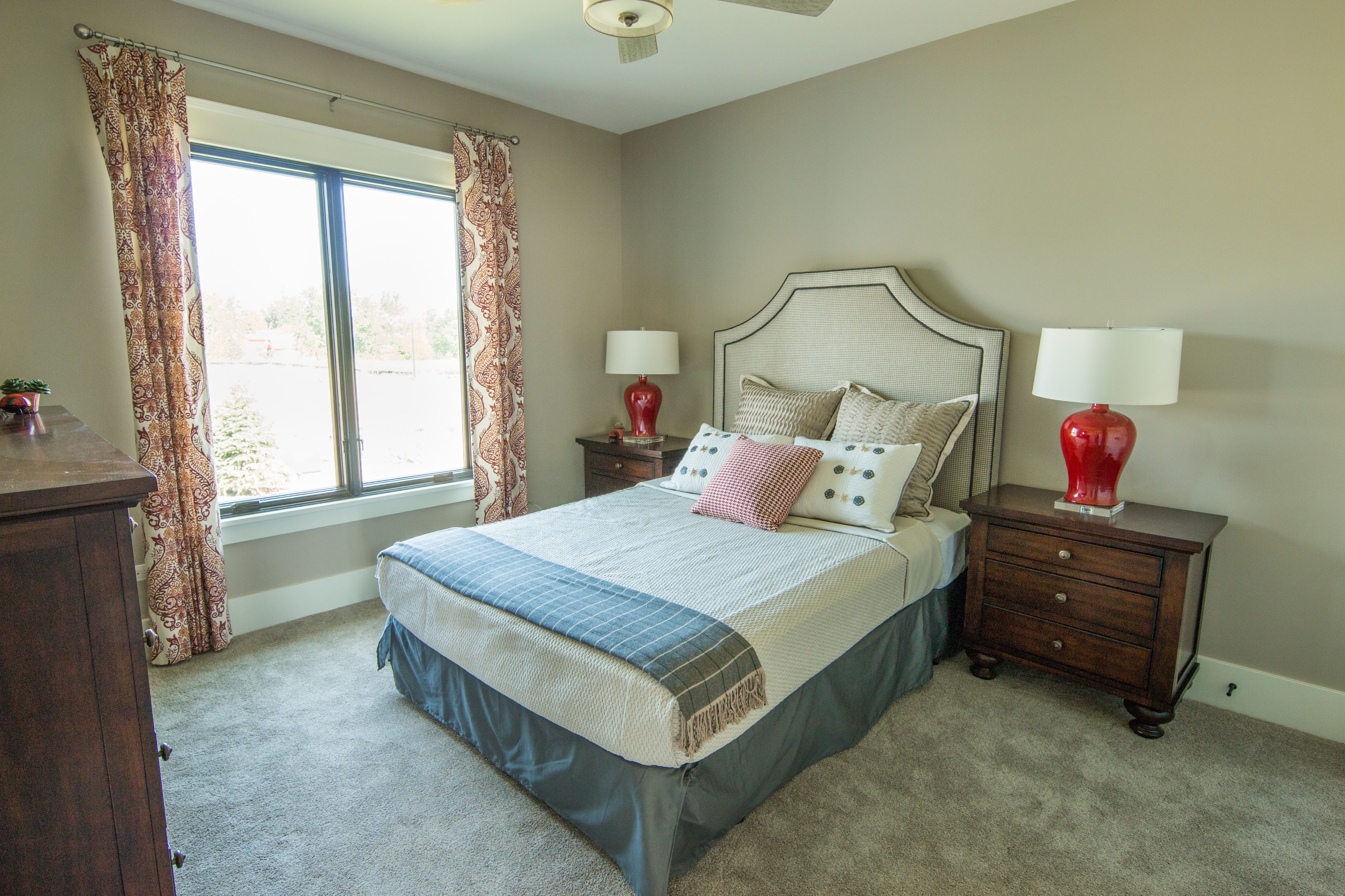 Guest room with upholstered headboard and red bedside lamps