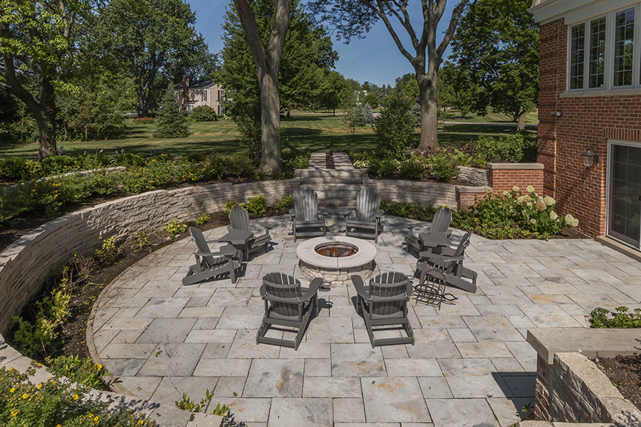 Firepit on sunken slate patio with eight grey adirondack chairs