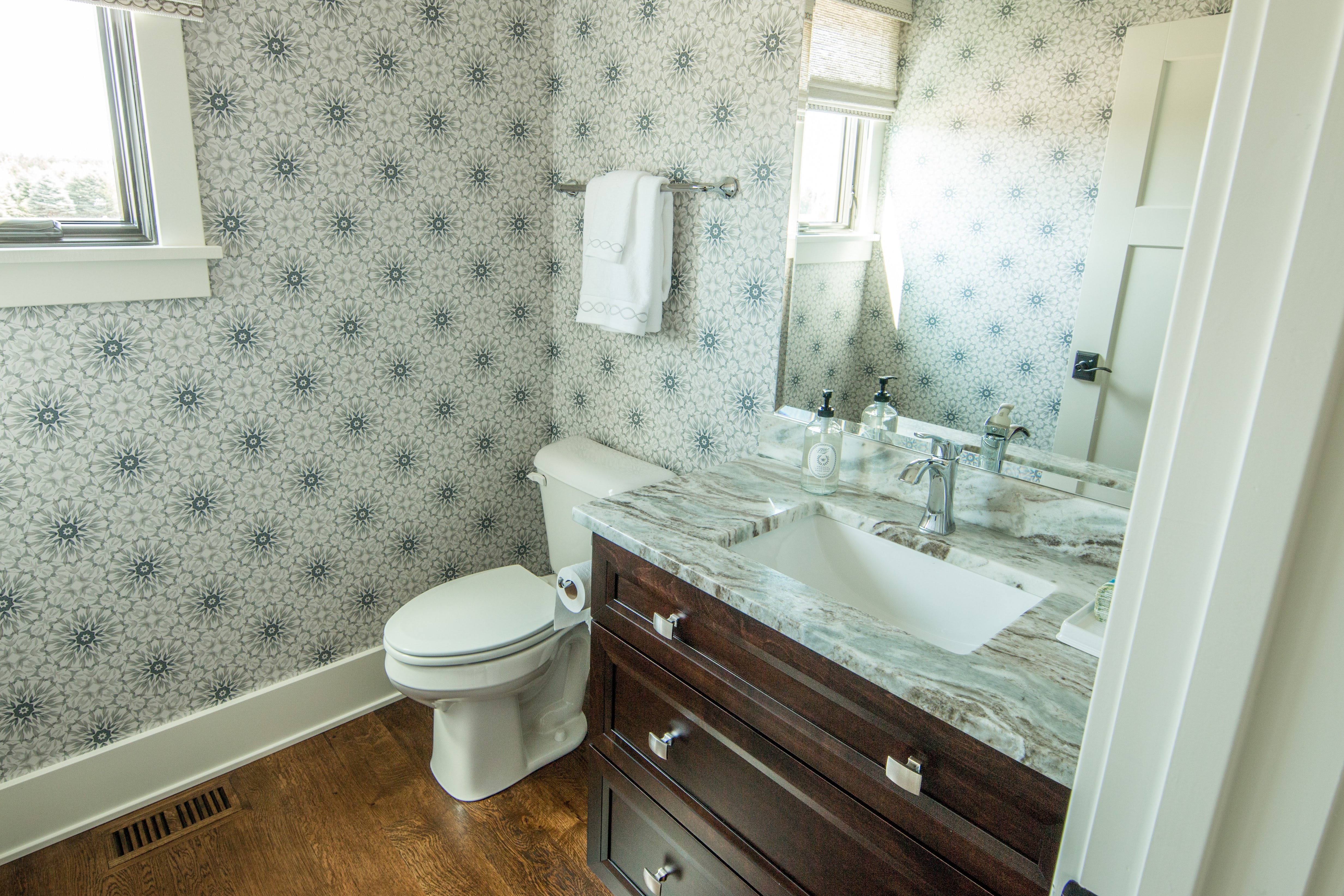 Guest bath with wallpaper, dark vanity and veined quartz counter