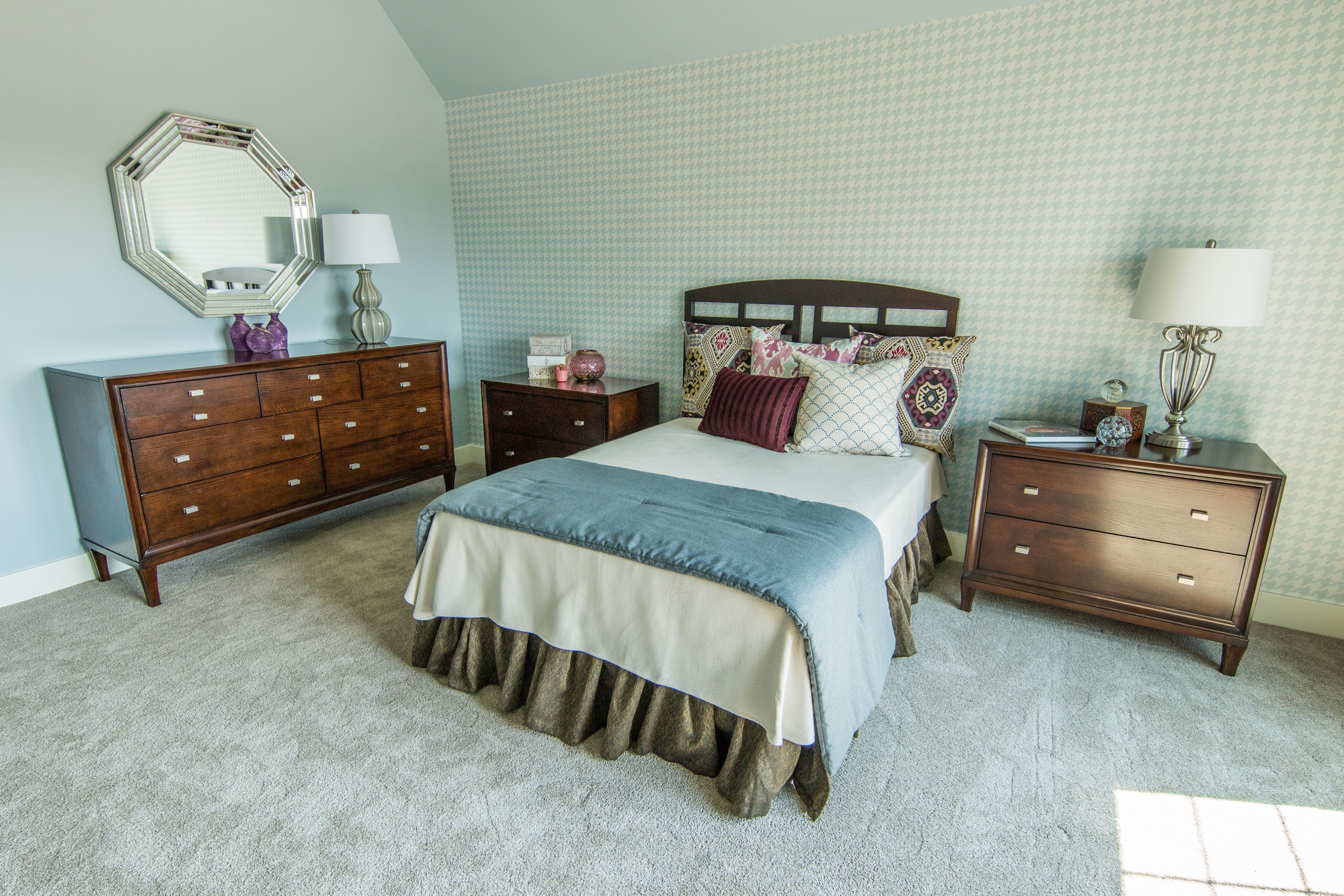 Guest bedroom with dark wood furniture and wallpaper behind bed
