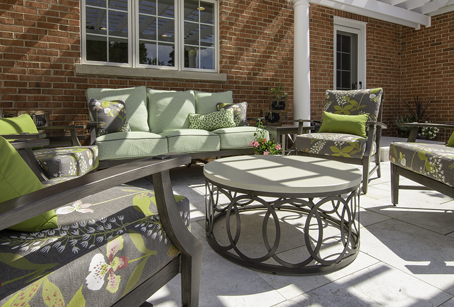 Patio furniture with grey and green floral cushions and round coffee table
