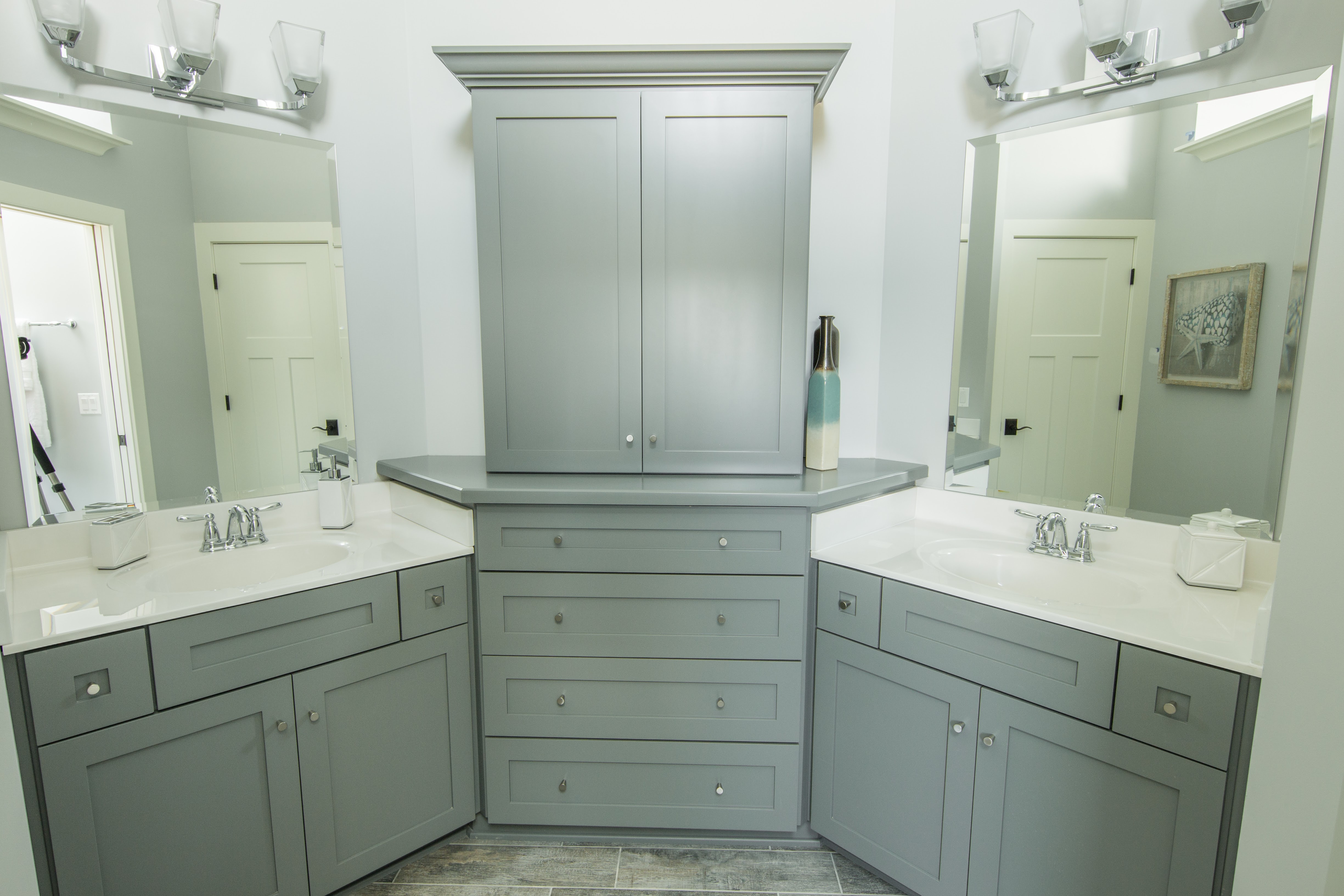 Shared bathroom space with two grey vanities and center storage tower