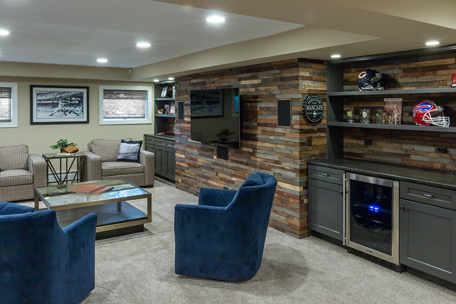 Basement family room feature wall with TV and bar fridge, with sports memorabilia displayed