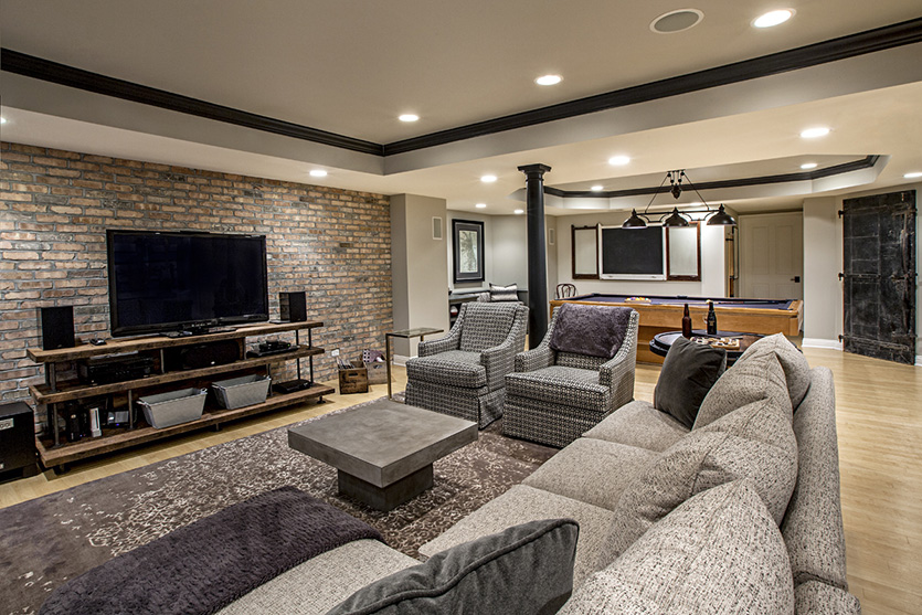 Basement family room remodel with pool table and grey upholstered seating