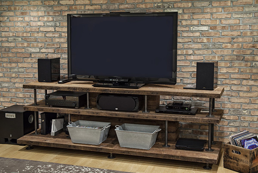 Large TV on rustic shelf in front of brick accent wall