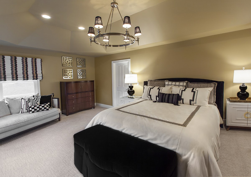 Main bedroom with tan walls and black and white bedding with chandelier