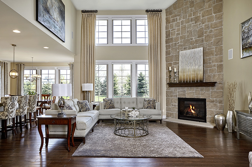Two story open living room with floor to ceiling windows and stone fireplace