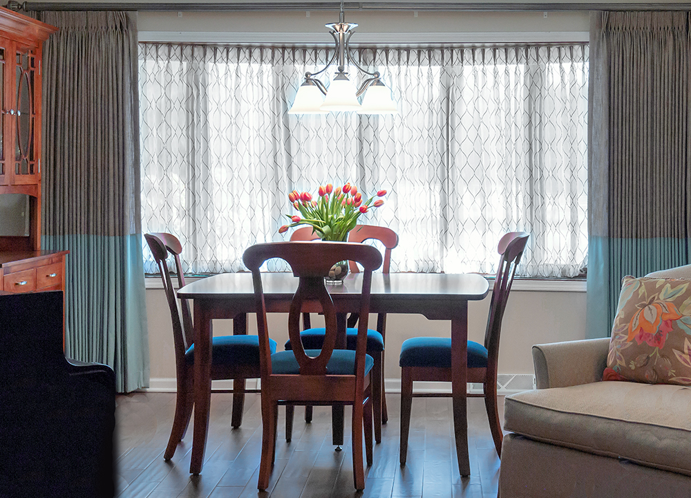 Dining room in front of picture window with blue and grey draperies