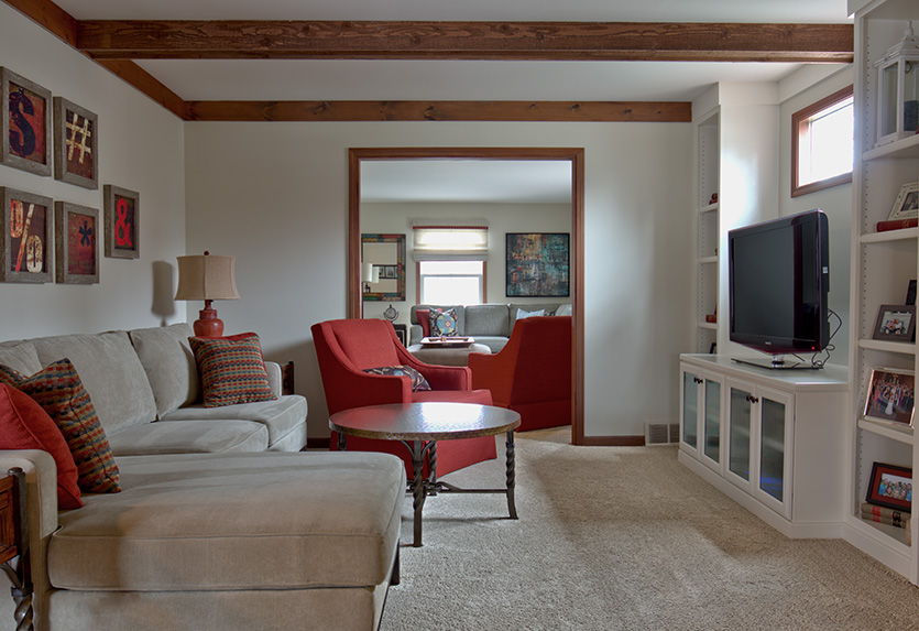 Family room with beige sectional, red chair and built in media shelving