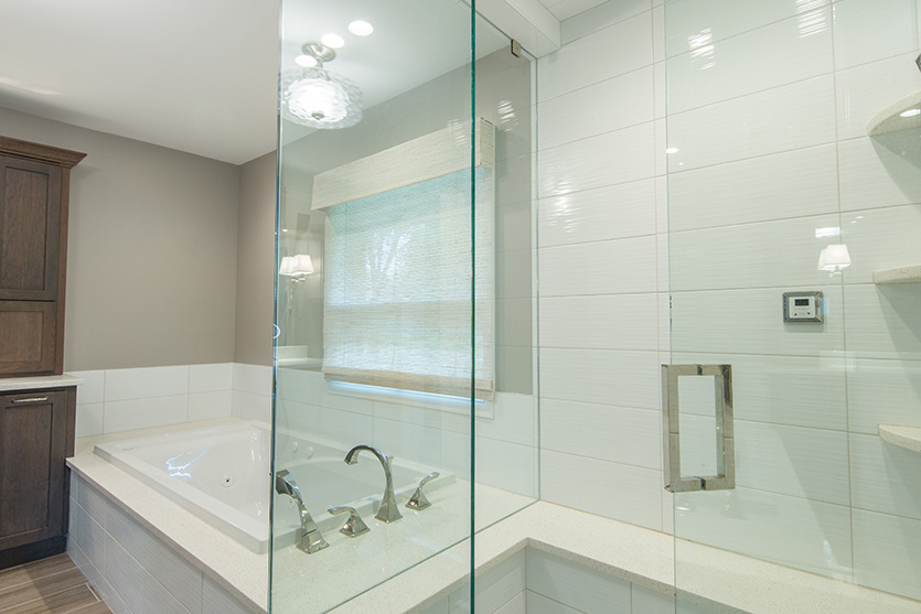 Main bath with separate tub and glass door shower with white tile and polished nickel fixtures
