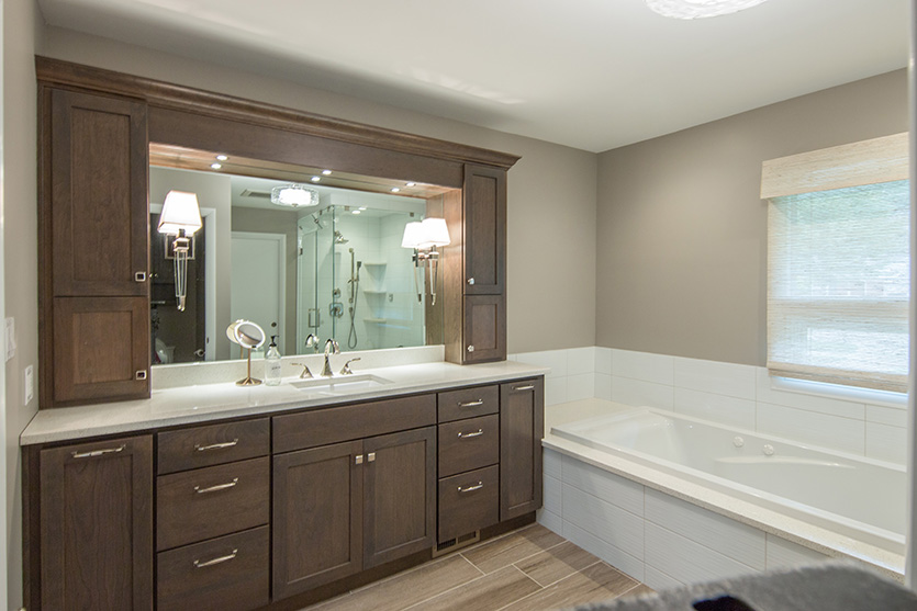 Main bath with large dark wood lighted vanity and white tub