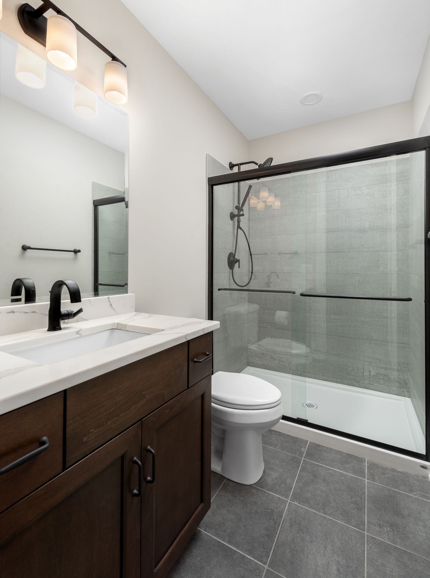 Guest bathroom with sliding glass shower doors and dark wood vanity