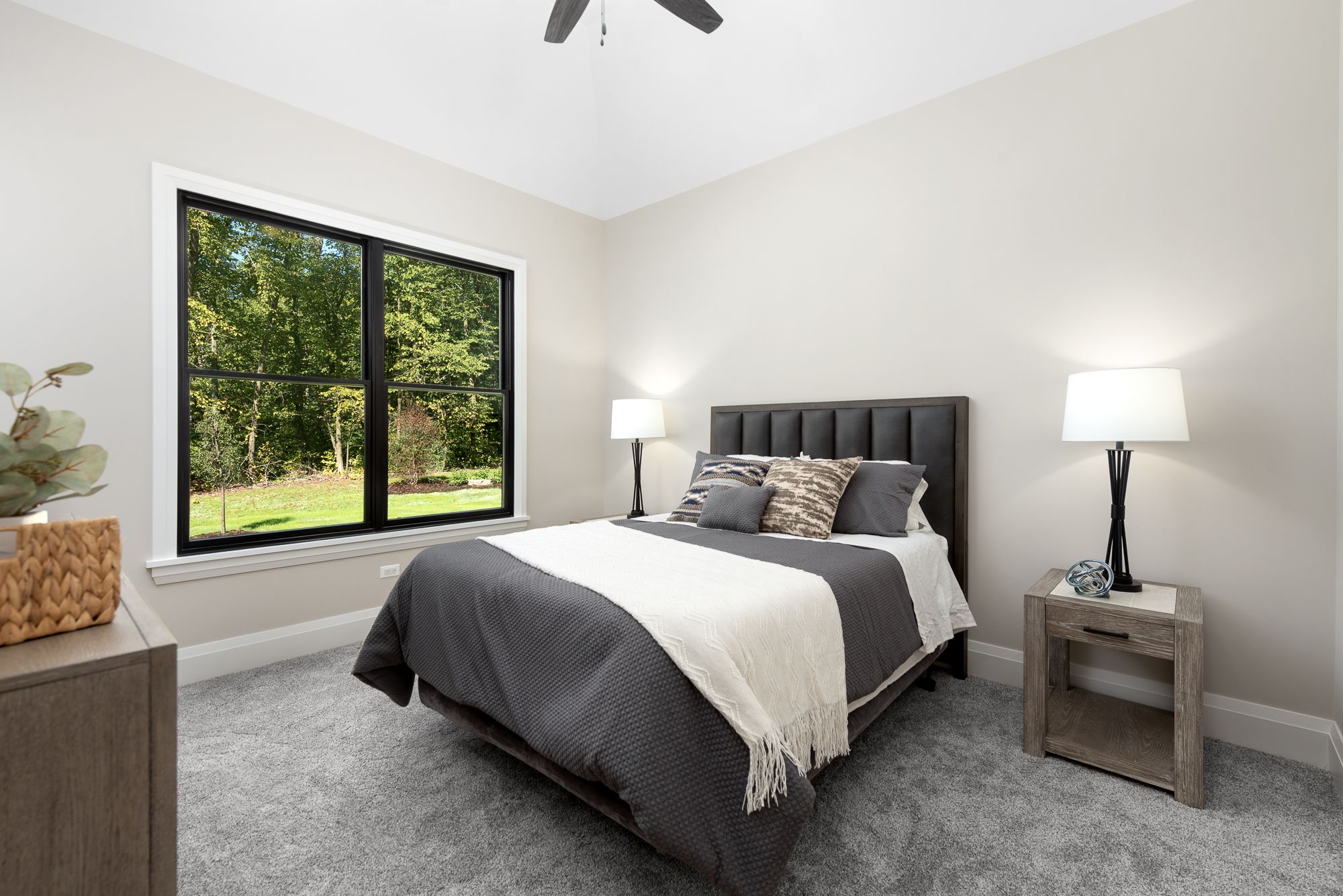 Guest bedroom with upholstered headboard and black framed windows