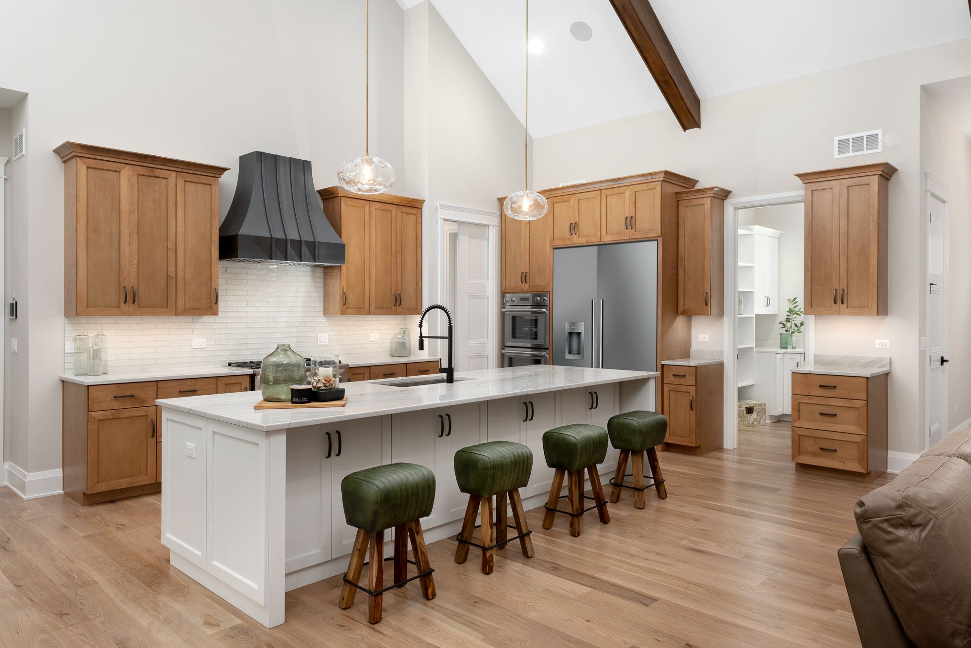 Modern farmhouse kitchen with high ceiling, wood beams and black vent hood