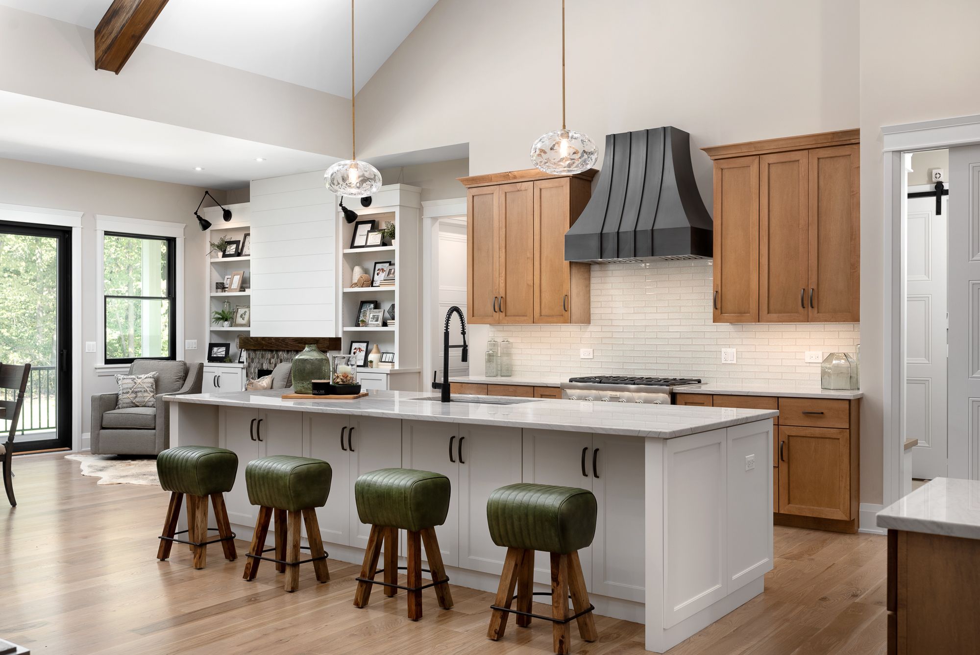 Open kitchen with white island, wood cabinets and green barstools