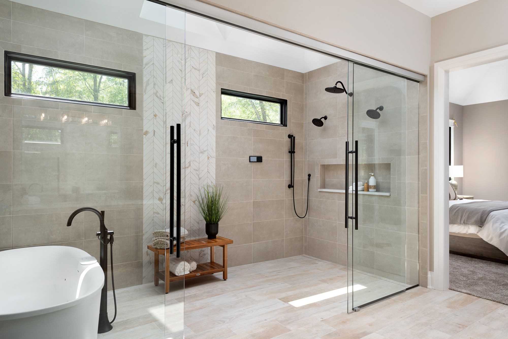 Wet room with glass doors, white tub and black plumbing fixtures